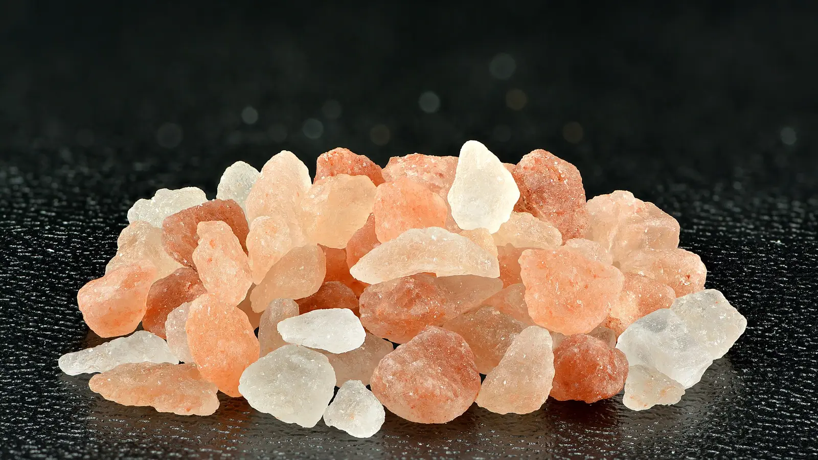 Grobe rosa und weiße Steinsalzkristalle auf dunklem Grund